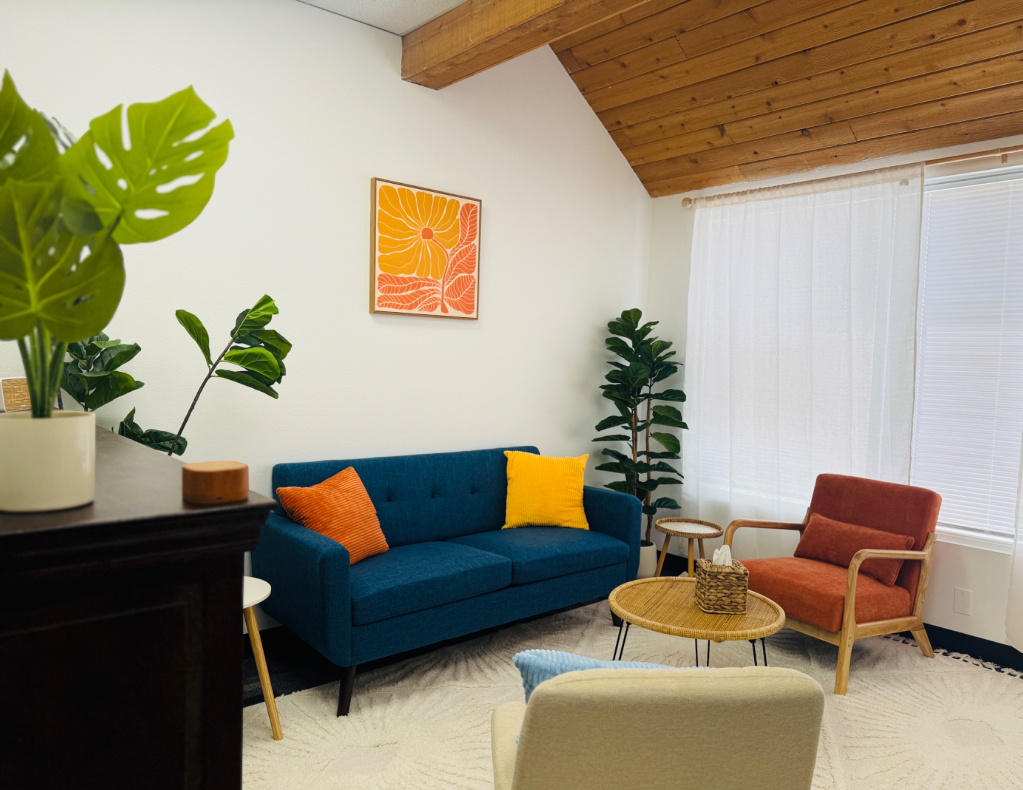 Warm mid-century modern therapy office with blue sofa and orange accents